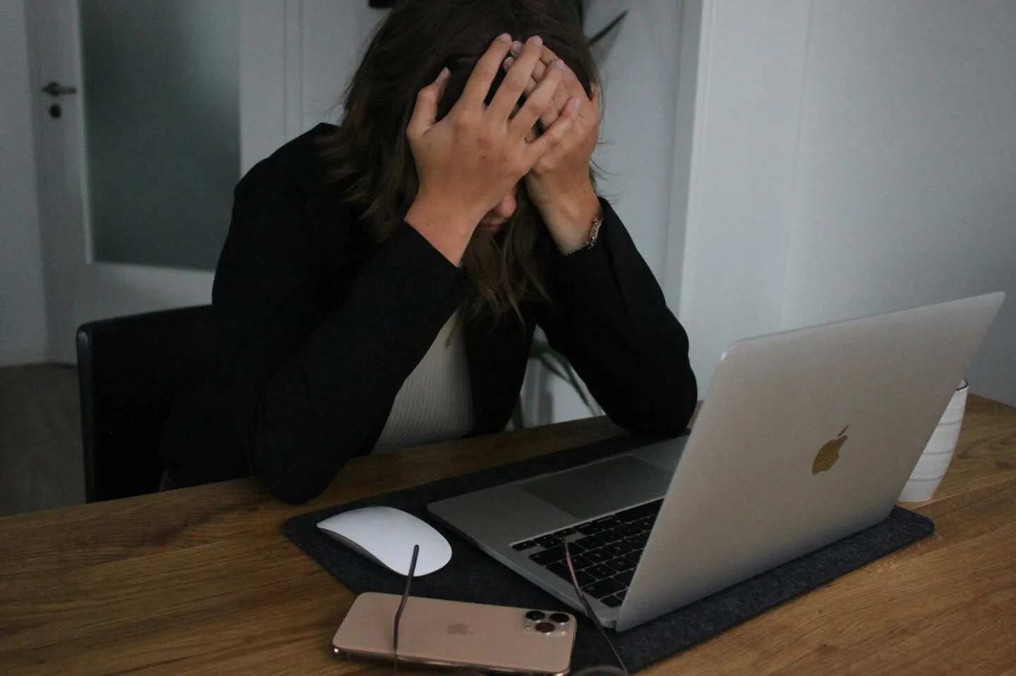 A woman at a laptop holding her head in her hands